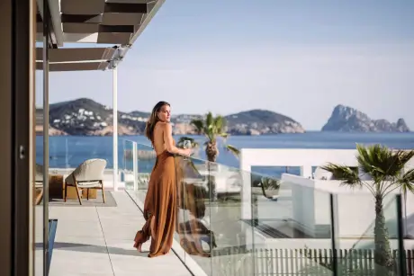Una mujer con un vestido marrón disfruta de la impresionante vista en 7Pines Resort Ibiza.
