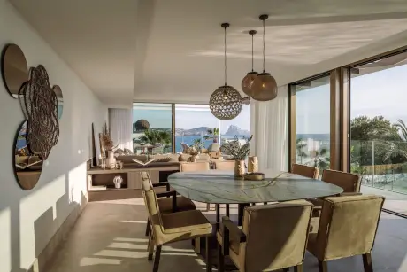 Elegante sala de estar con vista al mar, mesa moderna y elementos decorativos en 7Pines Resort Ibiza.
