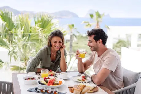 Pareja disfrutando del desayuno en 7Pines Resort Ibiza con vista al mar.