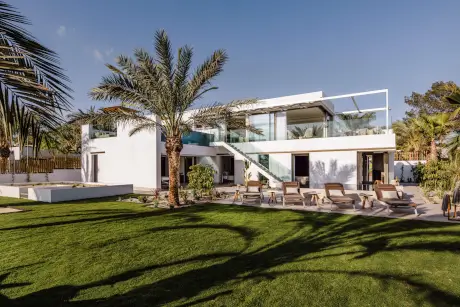 Villa contemporánea en 7Pines Resort Ibiza con jardín paisajístico y palmeras.