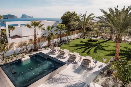 Jacuzzi y tumbonas en la terraza del jardín del 7Pines Resort Ibiza con impresionantes vistas al mar.