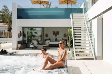 Paar, das am Pool im 7Pines Resort Ibiza entspannt und die luxuriöse Umgebung genießt.