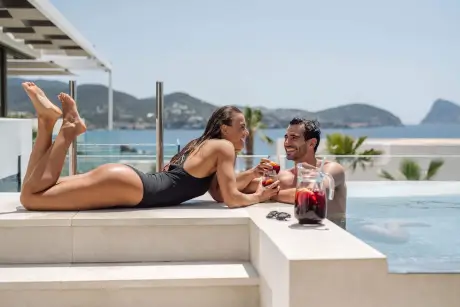 Pareja disfrutando de cócteles en la piscina del 7Pines Resort Ibiza.